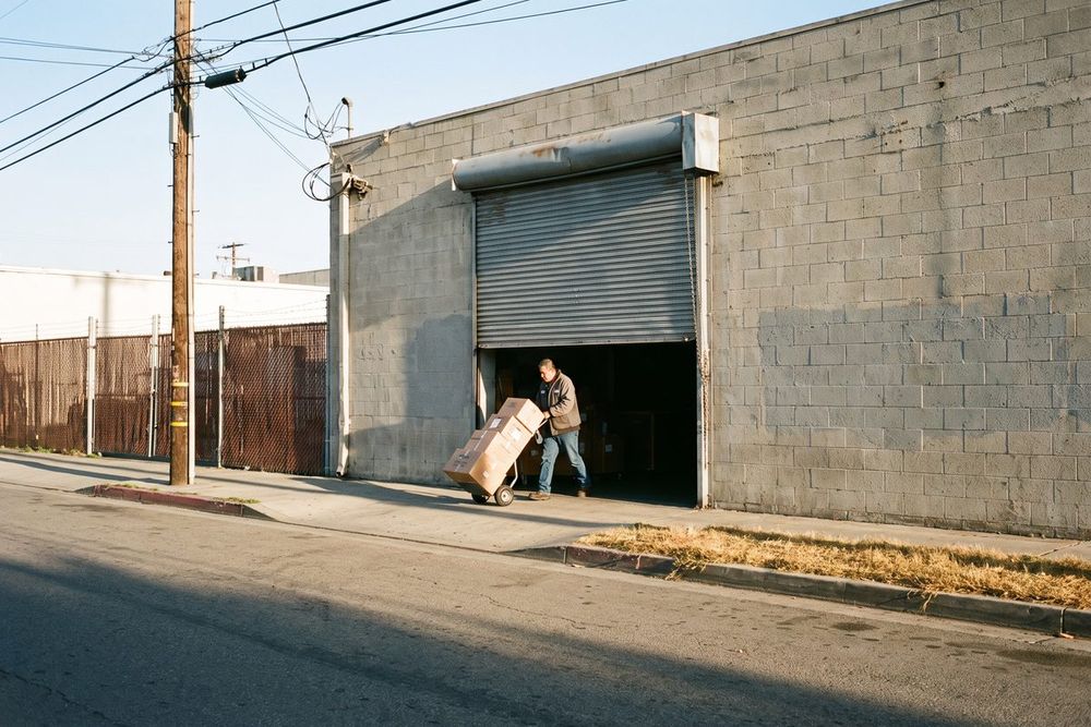A steel roll-up door half open on a small concrete block workshop